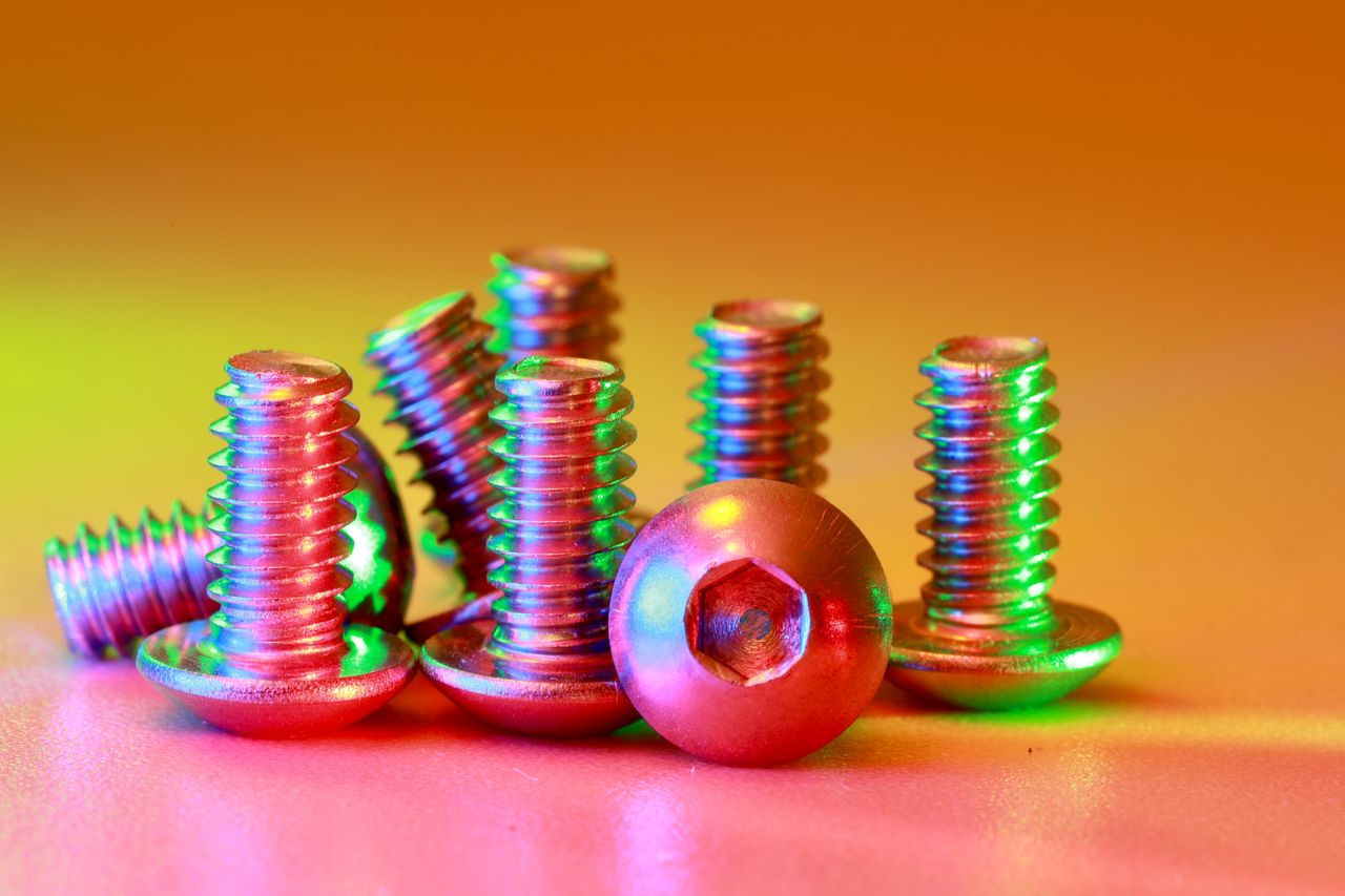 A close-up of colorful metallic screws on a vibrant, illuminated surface.
