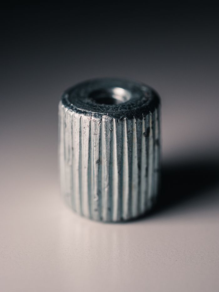 Detailed view of a metallic knurled nut with grooves, highlighting its texture and design.